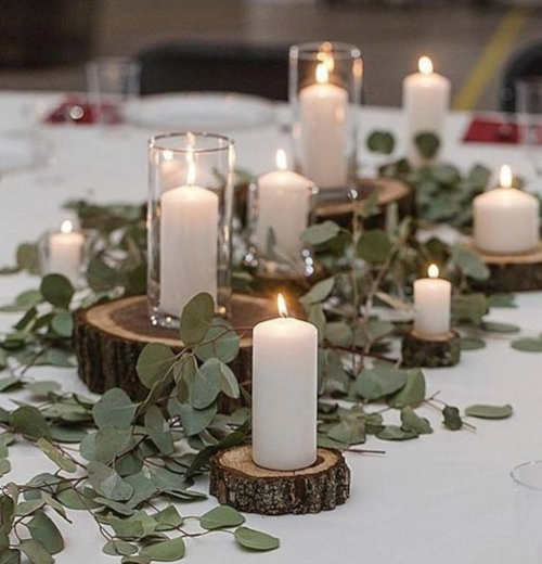 Tre candele nere sono su un tavolo con una pianta verde dietro di loro.